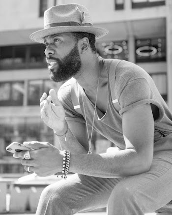 Grayscale Photo of Bearded Man Holding Smartphone While Sitting and Looking Away