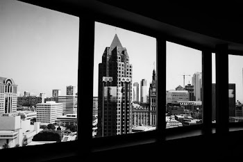 grayscale photo of buildings taken from inside another building