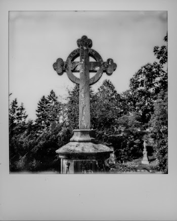 Grayscale Photo of Concrete Cross Near Trees