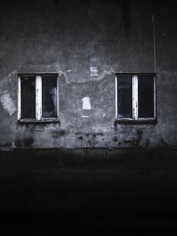 grayscale photo of concrete house with two windows