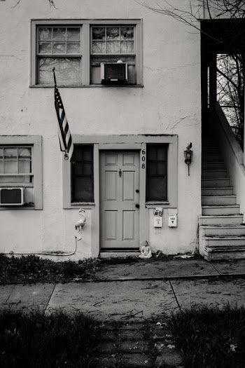 Grayscale Photo of Concrete House With Usa Flag