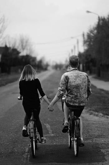 grayscale photo of couple riding bicycles on raod