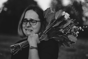 grayscale photo of crying woman holding bouquet of flowers