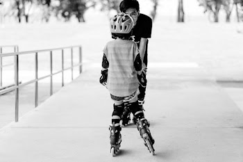 grayscale photo of man and girl using inline skates near railings