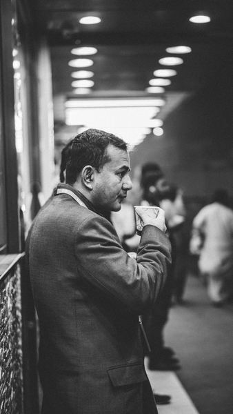 grayscale photo of man drinking on plastic cup