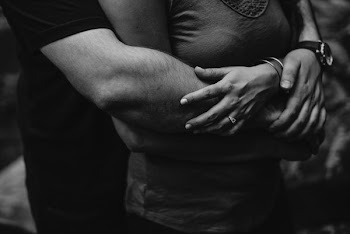 grayscale photo of man hugging a woman