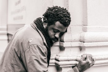 Grayscale Photo of Man Hugging Concrete Pillar