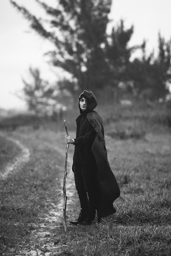 Grayscale Photo of Man in Black Coat Standing on Grass Field
