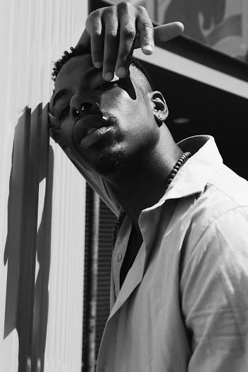 Grayscale Photo of Man Leaning on Wall
