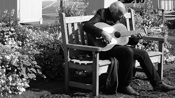 Grayscale Photo of Man Playing Guitar on Bench
