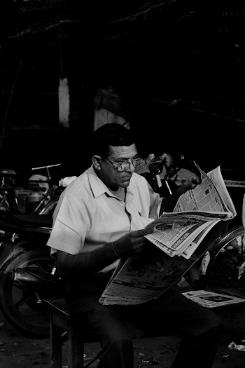 Grayscale Photo of Man Reading Newspaper