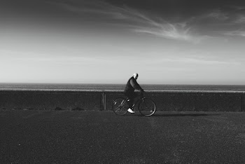 Grayscale Photo of Man Riding Bicycle