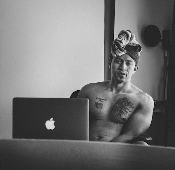 Grayscale Photo of Man Sitting Near Macbook Pro