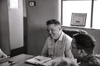 Grayscale Photo of Man Sitting on Chair
