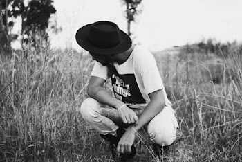 Grayscale Photo of Man Sitting on Grassland
