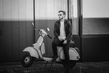 Grayscale Photo of Man Sitting on Motor Scooter Posing