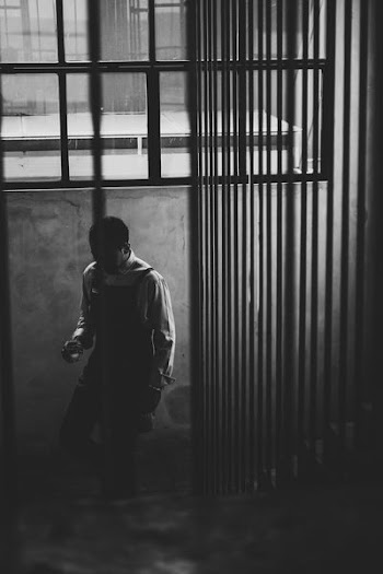 grayscale photo of man standing near concrete wall