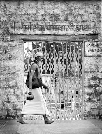 Grayscale Photo of Man Walking Beside Scissor Gate
