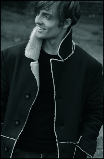Grayscale Photo Of Man Wearing Black Button-up Notch Lapel Coat Smiling