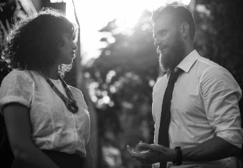 Grayscale Photo of Man Wearing Shirt Talking to Woman