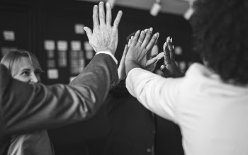 Grayscale Photo of People Doing High-five