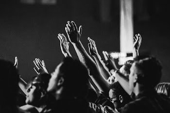Grayscale Photo of People Raising Their Hands