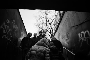 Grayscale Photo of People Walking Between Concrete Wall