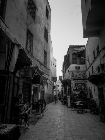 Grayscale Photo of People Walking on Street Between Buildings · Free Stock Photo