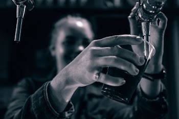 grayscale photo of person holding drinking glass