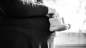 Grayscale Photo of Person Holding Pair of Toddler's Shoes