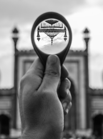 Grayscale Photo of Person Holding Round Magnifying Glass