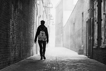 Grayscale Photo of Person Near Brick Wall