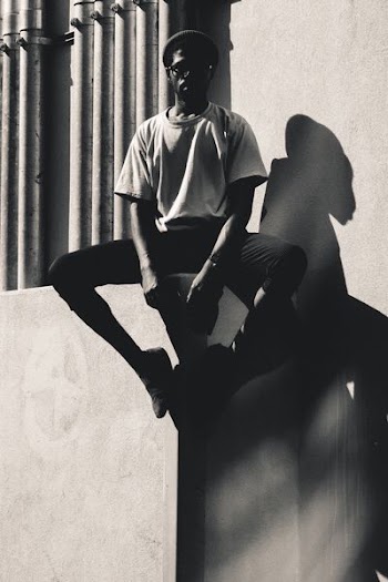 grayscale photo of person sitting on concrete pavement