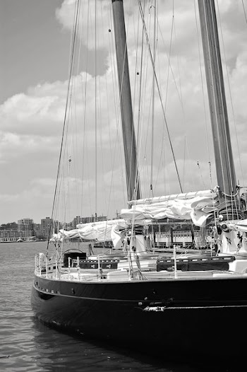 Grayscale Photo of Ship Near High-rise Mountains