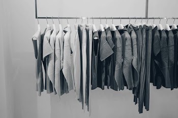 grayscale photo of shirts on rack