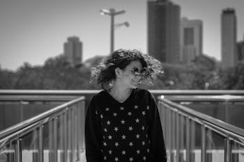 Grayscale Photo of Smiling Woman Wearing Star-print Long-sleeved Shirt Standing Between Metal Railings