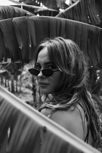 Grayscale Photo of Standing Woman Posing Beside Banana Trees While Looking Back