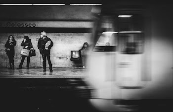 grayscale photo of three people standing on train station