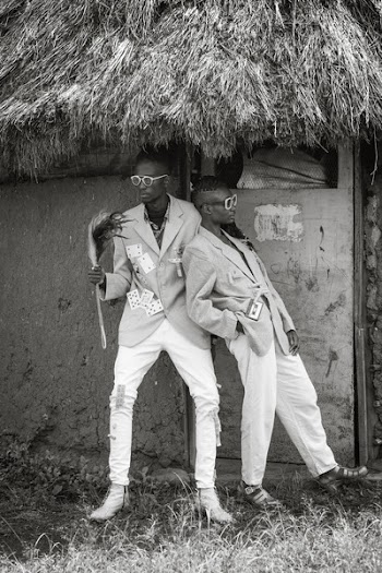 Grayscale Photo of Two Men Beside Wall