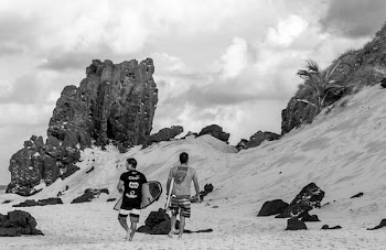 Grayscale Photo of Two Men Carrying Surfboards 