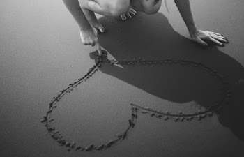 Grayscale Photo of Woman Drawing Heart on Sand