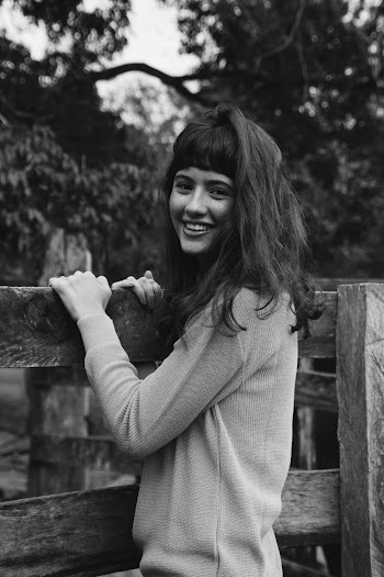 Grayscale Photo of Woman Holding Wooden Fence