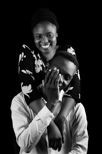 Grayscale Photo of Woman Hugging Man's Neck Inside Studio