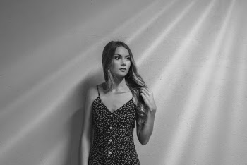 Grayscale Photo of Woman in Floral Dress Looking Away While Standing In Front of Wall 