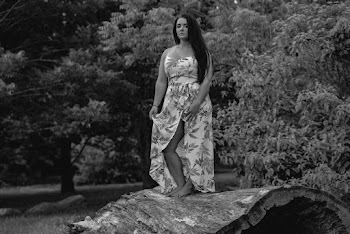 Grayscale Photo of Woman in Floral Dress Standing on Huge Hollow Log
