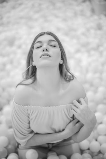 Grayscale Photo of Woman in Off-shoulder Top With Her Eyes Closed Posing in Ball Pit