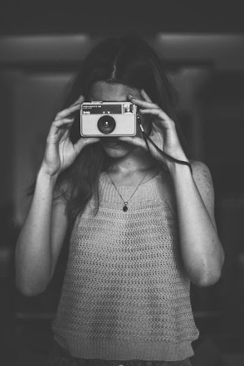 grayscale photo of woman in spaghetti strap top using camera