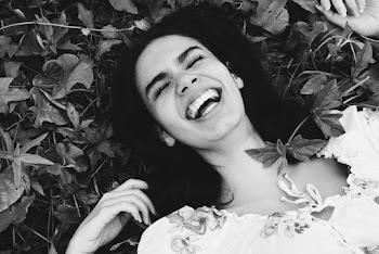Grayscale Photo of Woman Laughing While Sleeping on Plants