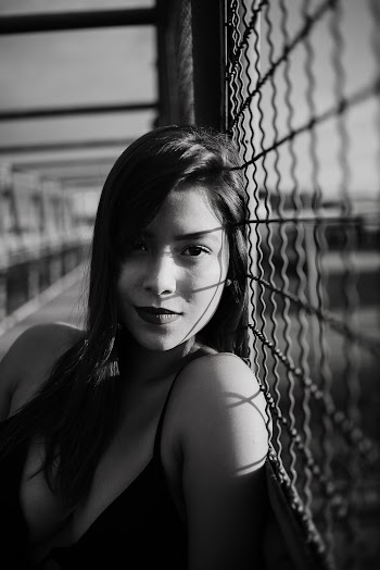 Grayscale Photo of Woman Leaning on Fence