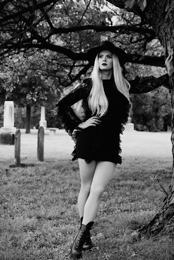 Grayscale Photo of Woman Leaning on Tree in Graveyard